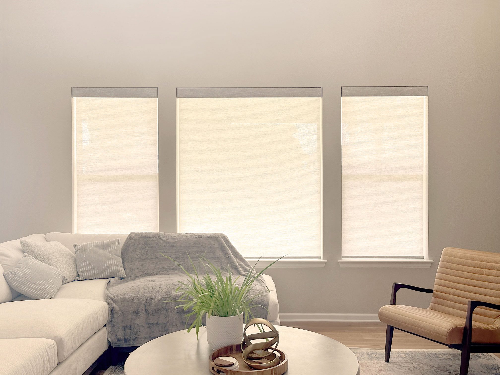 Designer roller shades for a bright living room with three large windows